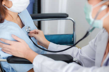 Asian female doctor is checking the symptoms of a female patient with a stethoscope in the disease...