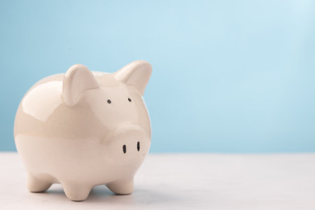 Cute piggy bank on white table with blue background. savings money concept.の写真素材