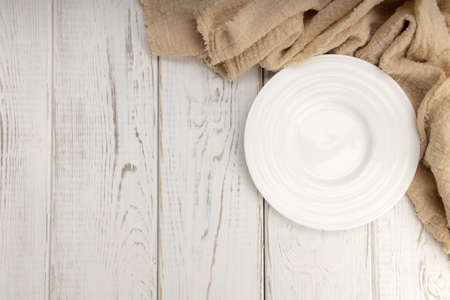 Top view of empty plate with fabric on white wooden table and copy space.の写真素材