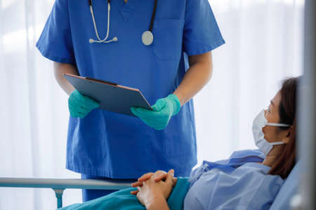 Close up The doctor is recording the condition of the patient. Asian female and male doctors wearing...