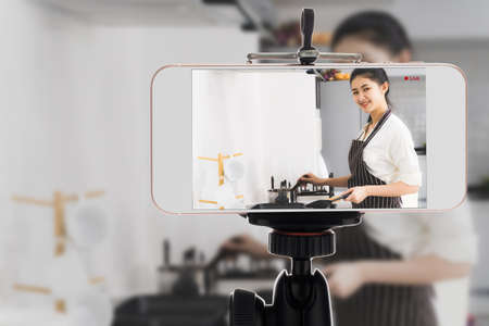 Blogger Asian women are beginning a home-based business to online teach cooking by smartphone. Work from home.の写真素材