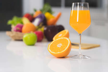 One glass of orange juice and a slice of orange on a white table in the kitchenの写真素材