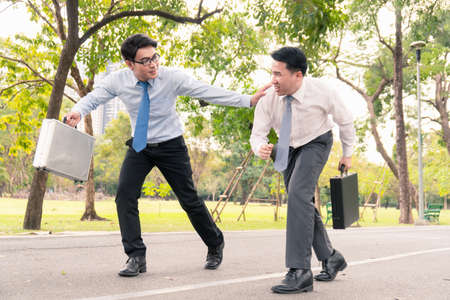 Two businessmen are race running in the park.
