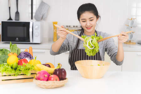 Young woman or housewife is happy to cooking salad, which consists of a variety of fruits and vegetables for the family.の写真素材