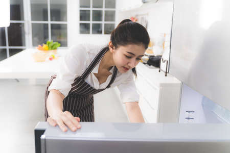 Beautiful Asian woman or housewife looking for ingredients in the fridge to prepare cooking for family.の写真素材