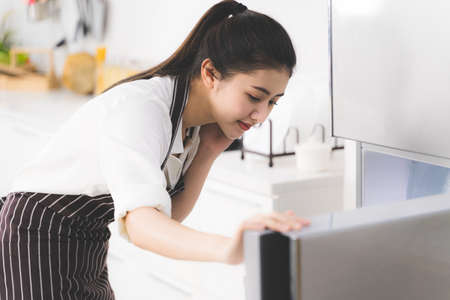 Beautiful Asian woman or housewife looking for ingredients in the fridge to prepare cooking for family.の写真素材