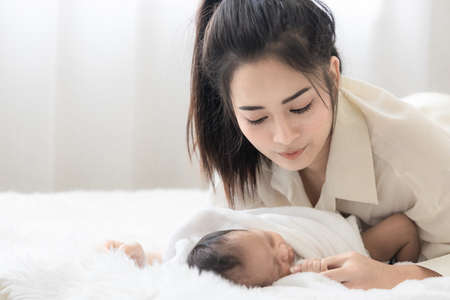 Asian young mother with cute newborn baby in bed. mother 's day concept.の写真素材