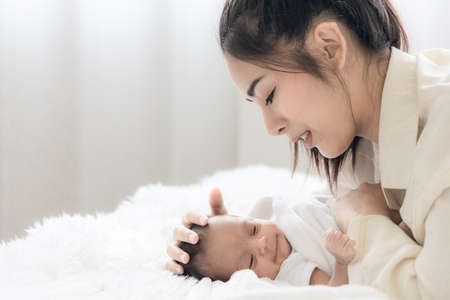 Asian young mother with cute newborn baby in bed. mother 's day concept.の写真素材