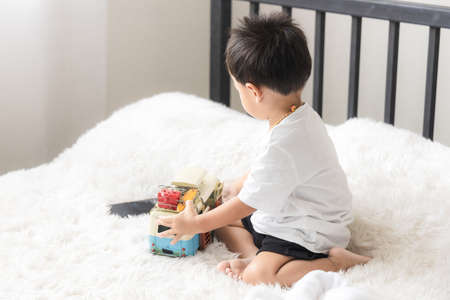 Asian little boy, the son playing car toy in bed room.の写真素材
