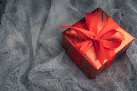 Red gift box on fabric background with copy space for your greeting.の写真素材