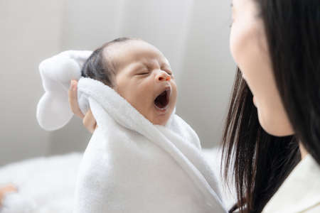 Portrait of cute newborn baby yawning her mother. Wife and mother's day concept.の写真素材