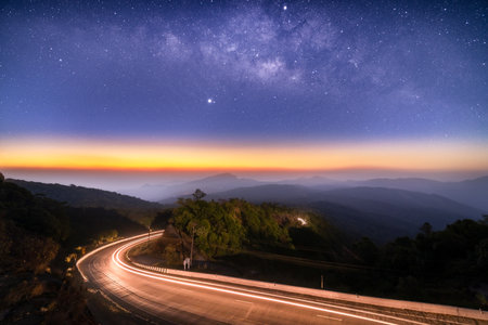 Milky Way Galaxy with lighting on the road and layer of mountain at Doi inthanon Chiang mai, Thailandの写真素材