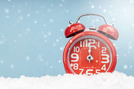 Red alarm clock  placed on fake snow and blue background. copy space for your greetings.の写真素材