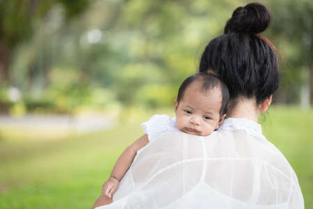 Portrait of baby in the mother's embrace in the park. concept of duties of wife and mother in raising children and family.の写真素材