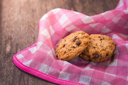 Chocolate chip cookies with pink cloth on wooden table.の写真素材