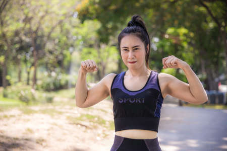 Portrait rear of an Asian woman wearing a black sports bra and she is body warm up for a workout by running in the park. Urban health care concept.の写真素材