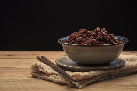Cook Ripe Berry Rice in a bowl with wooden chopsticks on wood table with a black background. Brown...