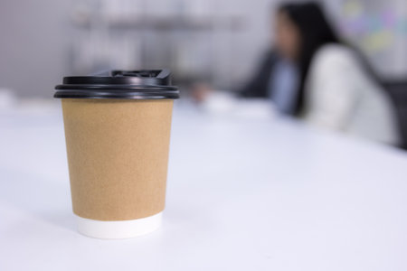 Paper cup of coffee on white table in office. Recycle coffee cup container. cup for taking hot...