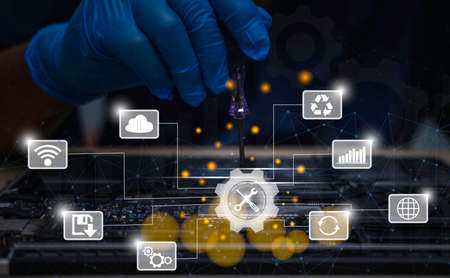 technician wearing rubber gloves is fixing and checking a broken notebook with a screwdriver. Maintenance and technology concept.の写真素材