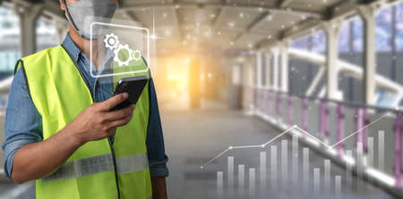 Young engineers are using smartphones and technology to help manage tasks. male worker is using an app-based command system. wireless technology concept.の写真素材