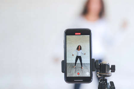 Young black woman created her dancing video content by smartphone camera to live streaming to social media application for view, like and share. stay at home to protect spread of coronavirus covid-19.の写真素材