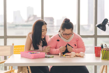 young girl with autism is practicing fun playing with toys at home with his mother. Autistic young students are learning with teachers happily.の写真素材