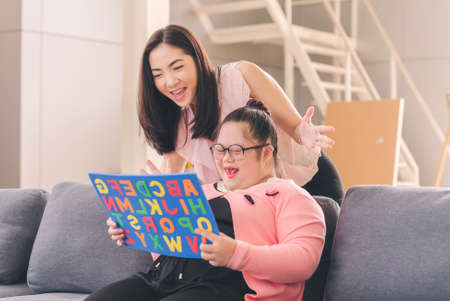 young girl with autism is practicing fun playing with toys at home with his mother. Autistic young students are learning with teachers happily.の写真素材