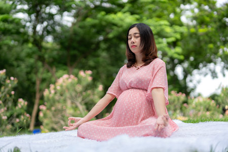Portrait of asian pregnant woman relaxing by meditating in parkの写真素材