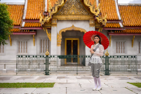 Portrait of beautiful young woman wearing Thai Rattanakosin national costume in a temple built according to Thai art in Thailandの素材