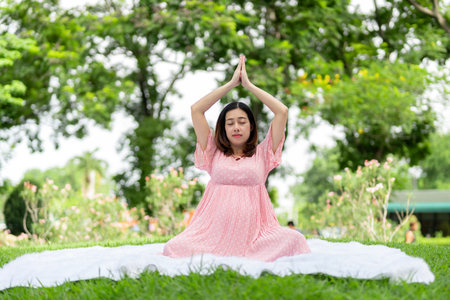Portrait of Asian pregnant woman relaxing doing yoga in the parkの写真素材