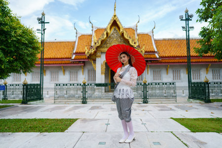 Portrait of beautiful young woman wearing Thai Rattanakosin national costume in a temple built according to Thai art in Thailandの素材