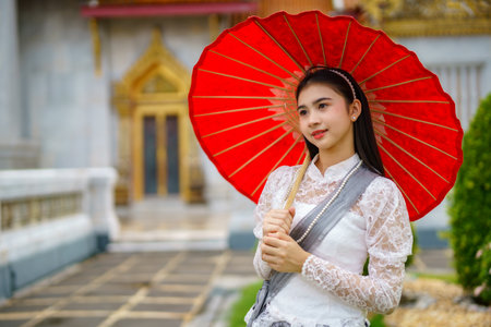 Portrait of beautiful young woman wearing Thai Rattanakosin national costume in a temple built according to Thai art in Thailandの素材