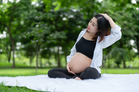 Portrait of Asian pregnant woman relaxing doing exercise in the parkの写真素材