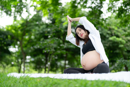 Portrait of Asian pregnant woman relaxing doing yoga in the parkの写真素材