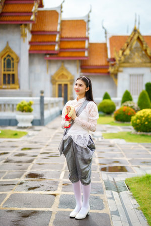Portrait of beautiful young woman wearing Thai Rattanakosin national costume in a temple built according to Thai art in Thailandの素材