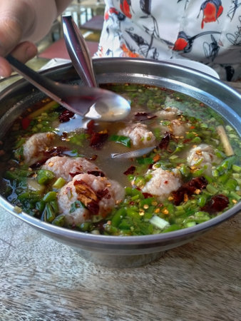 Thai spicy soup with pork and shrimp in a pot on wooden tableの写真素材