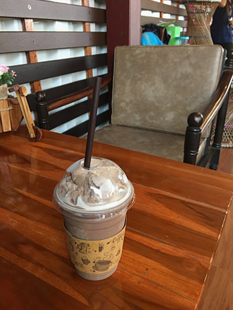 Iced coffee in plastic cup on wooden table in coffee shop.の写真素材