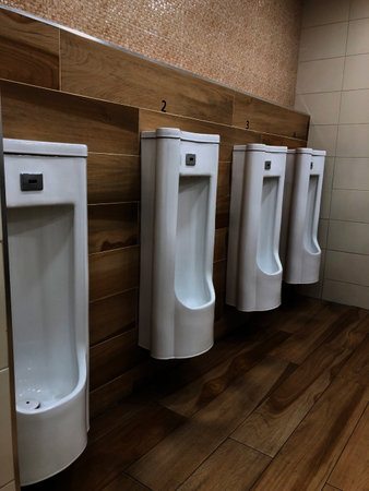 interior of a modern restroom with white urinals and wooden walls