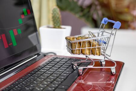 shopping online concept. gold coins in shopping cart with market graphの写真素材