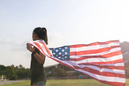A Young asian woman holding American flag on blue sky background