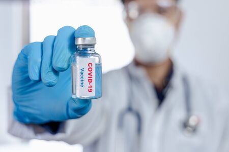 Healthcare cure concept. a doctor hold vaccine on hand in blue medical gloves. during Coronavirus crisis, Covid 19 virus, vaccine vialの写真素材
