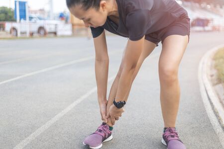 the runner woman injured after running. She is touching on Ankle that is painful area.の写真素材