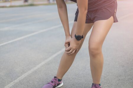 the runner woman injured after running. She is touching on knee that is painful area.の写真素材