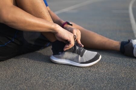 Running shoes. closeup of man tying shoe laces. Sport fitness runner getting ready for jogging in the running track.の写真素材
