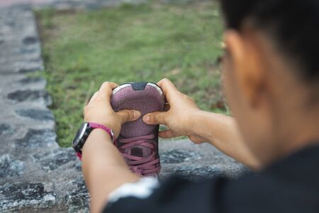 The Young female workout before fitness training session at the park. Healthy young woman warming up outdoors.の写真素材
