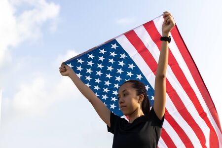 A Young asian woman holding American flag on blue sky backgroundの写真素材