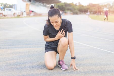 The women are tired after running hard on the running track. She is touching on the heart area.の写真素材