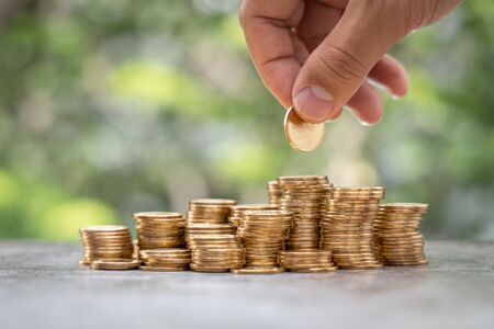 Money Financial Business Growth concept Man hand put money gold coins to stack of coinsの写真素材