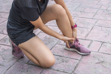 The young sport woman holding Ankle in pain suffering muscle injury after running.の写真素材