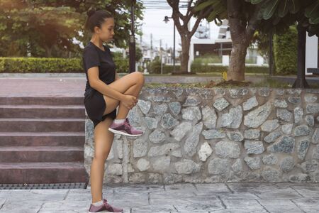 The Young female workout before fitness training session at the park. Healthy young woman warming up outdoors.の写真素材